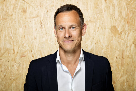Portrett av Christian Bason, i bakgrunnen en vegg av kryssfinér.