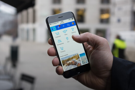 Bildet viser en hånd som holder en mobil med finn.no app i bruk