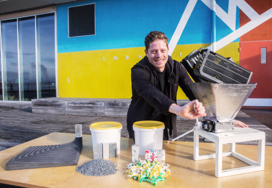 Bilde av mann bak et bord som bruker en kvern. Oppi kvernen og på bordet ligger forskjellig plastmateriale.