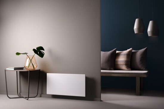 Interiør med bord, panelovn, lamper, sofa og puter.
