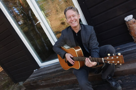 Alan AtKisson med gitar på terrasse