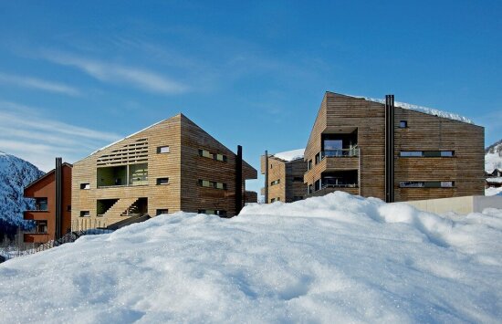 Blå himmel, brune bygninger, fjellandsby, snø