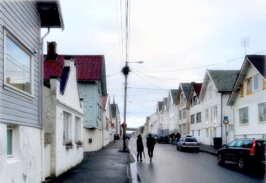 To personer står i en bygate i Haugesund omgitt av lave trehus