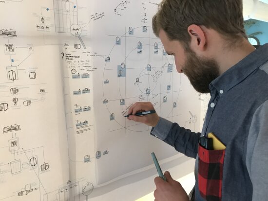 Adrian Paulsen fra Halogen skisserer på en illustrasjonstegning som henger på veggen.
