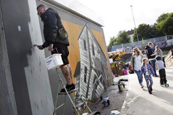 Street art kunstneren GRISK som maler oppe på en vegg.