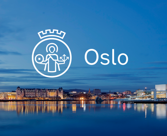 Oslo sett fra sjøen en sommerkveld. Oslo havnelager og andre bygninger speiler seg i vannet. Forslaget til ny logo for Oslo kommune er i hvitt, plassert midt på bildet.