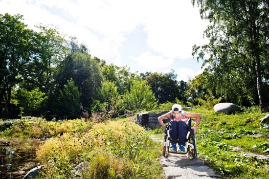 Gutt i rullestol ute i naturen.