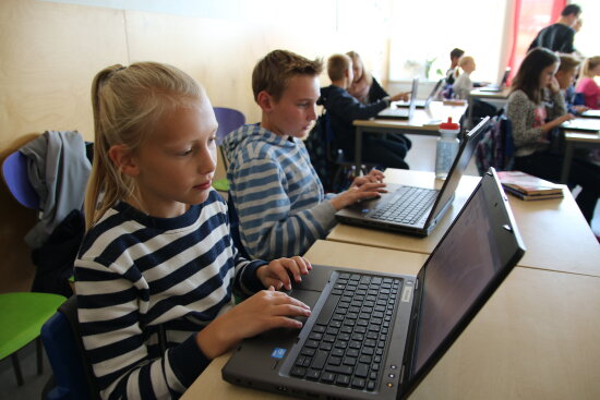 En jente og en gutt sitter foran hver sin PC i klasserommet