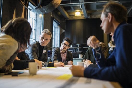 Mennesker diskuterer i workshop rundt bord.