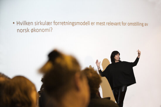 Susanne Ringdal står foran et hvitt lerret og holder foredrag